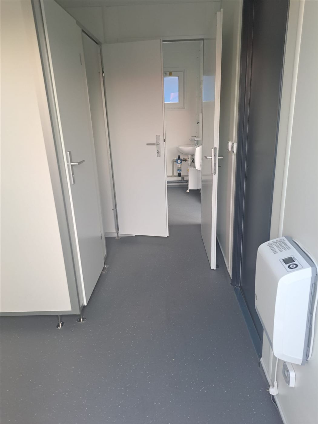 Flur im Sanitärcontainer mit Kabinentüren und Heizung