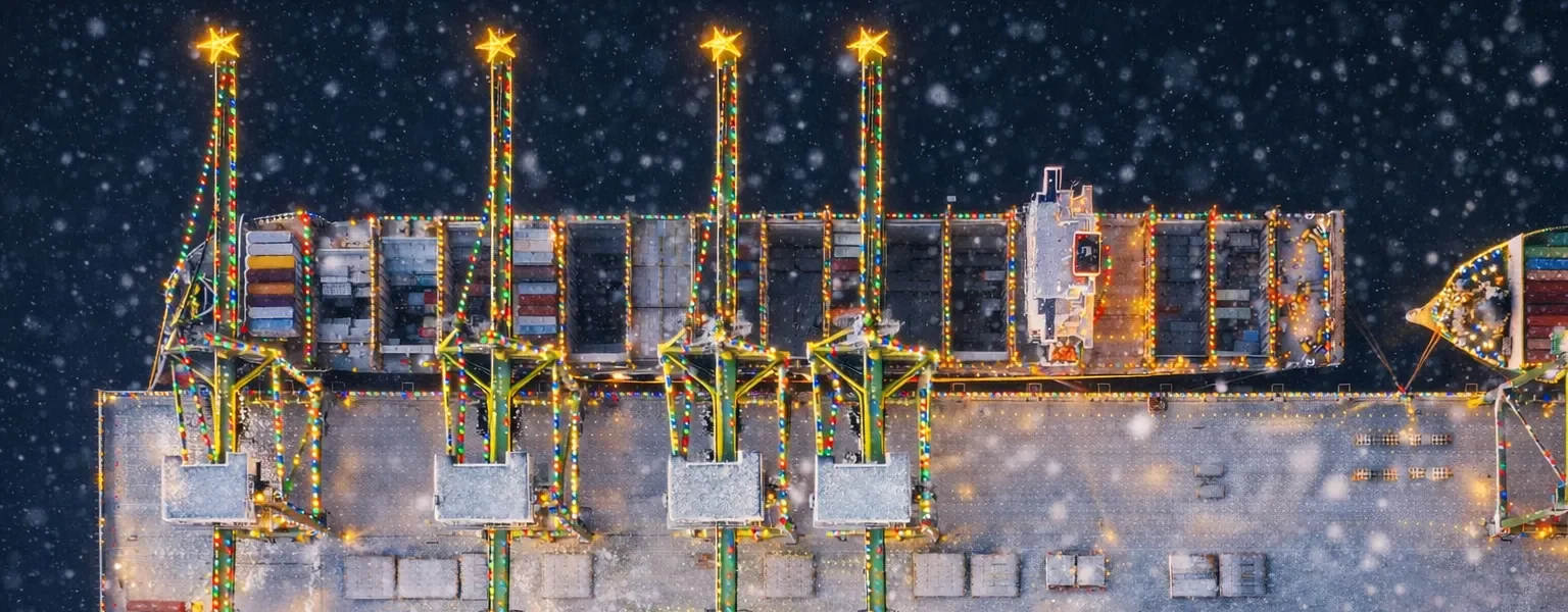 Winterlicher Containerhafen mit Schnee und Weihnachtsbeleuchtung aus der Vogelperspektive