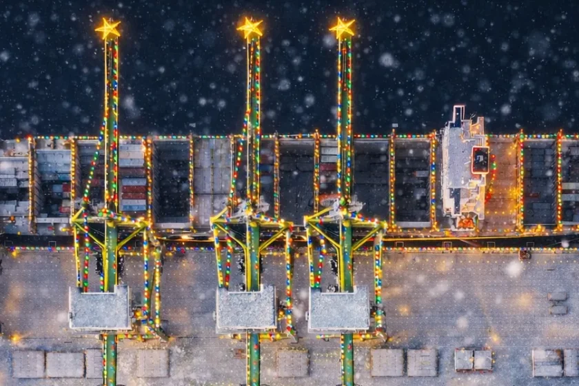 Winterlicher Containerhafen mit Schnee und Weihnachtsbeleuchtung aus der Vogelperspektive