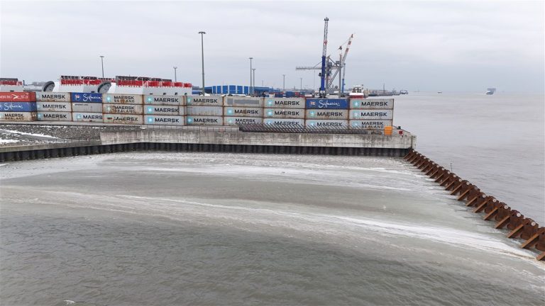 Containerwand aus gebrauchten Containern am Hafenbecken